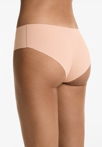 Naadloze huidskleurige ondergoed met een hoge uitsnijding, voorzien van een soepele stof en een minimalistische elastische tailleband.