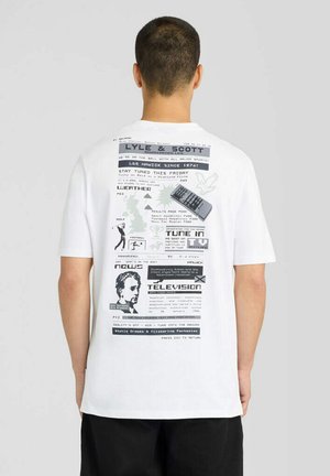 Man gezien van achteren die een wit T-shirt draagt met zwarte en grijze tekst, afbeeldingen en een illustratie van een afstandsbediening op de rug.