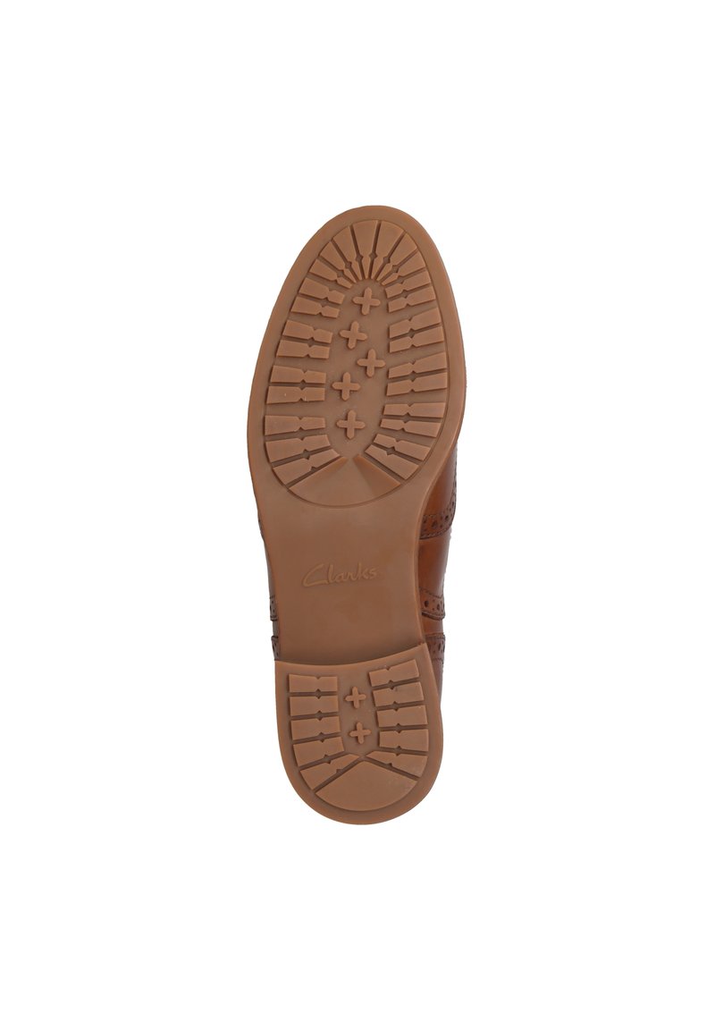 Suela de zapato de cuero marrón con una suela de goma texturizada que presenta un patrón de cinta para tracción. Incluye el logotipo en relieve "Clarks".