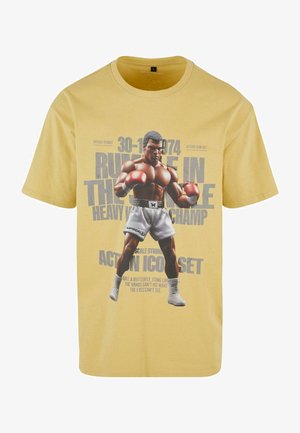 Gelbes Baumwoll-T-Shirt mit einem grafischen Druck eines Boxers mit Handschuhen, Text mit Veranstaltungsdatum und Slogan darunter, kurze Ärmel und Rundhalsausschnitt.