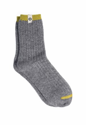 Par de calcetines grises acanalados de longitud media con puños amarillos y pequeño detalle amarillo en la punta, mostrados sobre un fondo blanco.