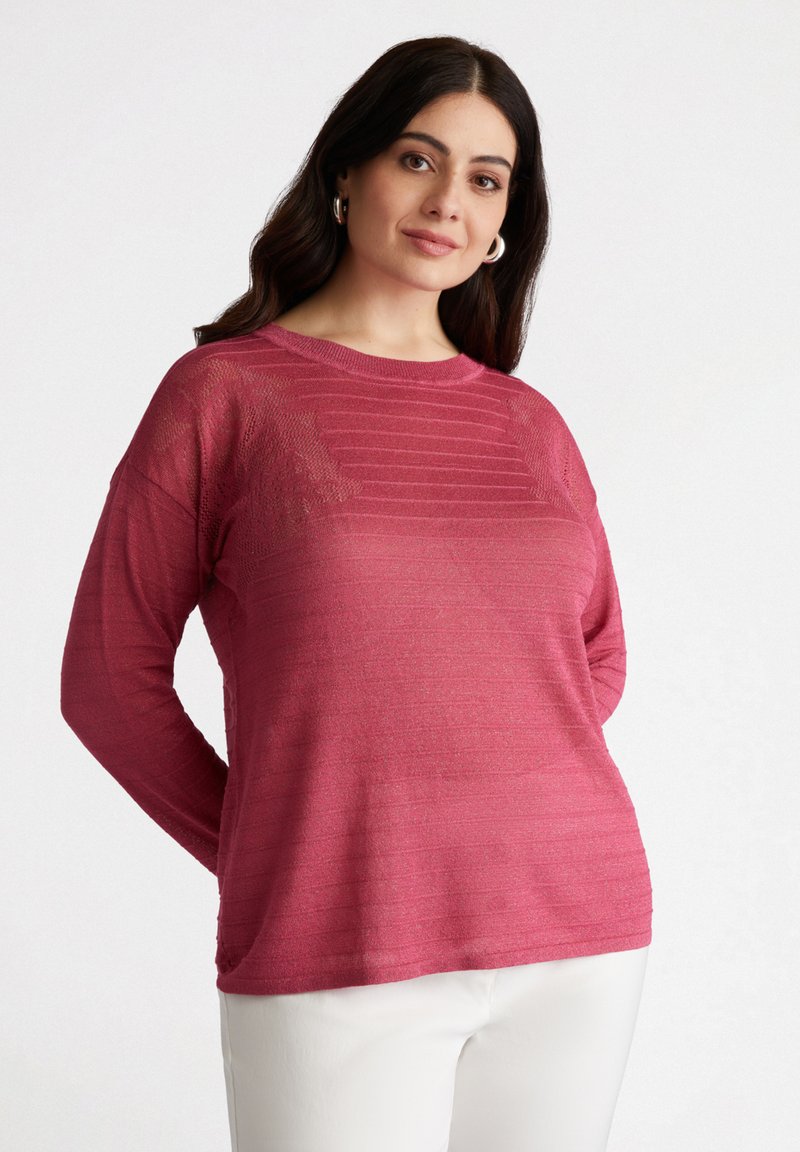 Pullover a maniche lunghe, con texture, di un intenso colore rosa con righe orizzontali. Materiale morbido, vestibilità rilassata, abbinato a pantaloni bianchi.