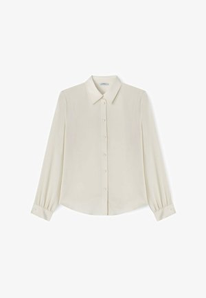 Blouse crème à manches longues avec col pointu, patte de boutonnage à l'avant et poignets boutonnés, présentée à plat sur un fond blanc.