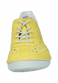 Zapato de gamuza amarilla con diseño perforado, punta redonda, cordones grises y suela de goma blanca. Presenta costuras decorativas alrededor de los bordes.