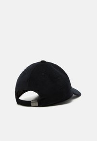 Svart kordfløyels-baseballcaps med buet brem, justerbar stropp bak og en metallisk logoaccents. Teksturert stoff.