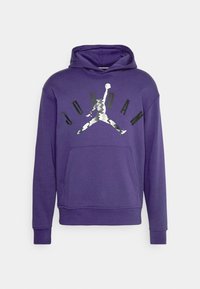 Sweat à capuche violet avec poche avant présentant un logo Jumpman motif camouflage et le mot « JORDAN » en lettres noires au-dessus.
