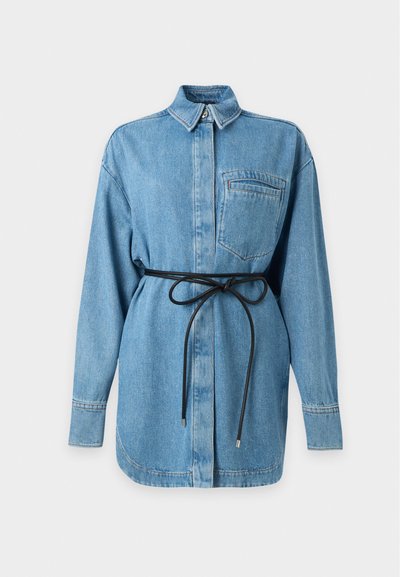 Robe chemise en denim bleu clair, manches longues, poche poitrine, ceinture noire nouée à la taille et col boutonné.