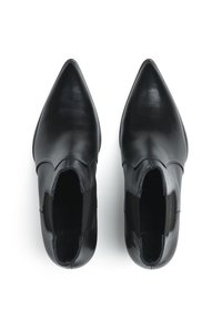 Bottes courtes en cuir noir, bout pointu, panneaux élastiques sur les côtés, texture lisse et détails de coutures discrètes.