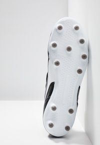 Botas de fútbol negras con un upper texturizado, suela blanca y seis tacos receptivos. Presenta un diseño aerodinámico con un aspecto de perfil bajo.