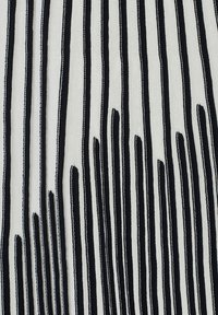 Tessuto con righe verticali in bianco e nero, di ampiezze variabili. Il materiale appare leggero con una texture liscia.