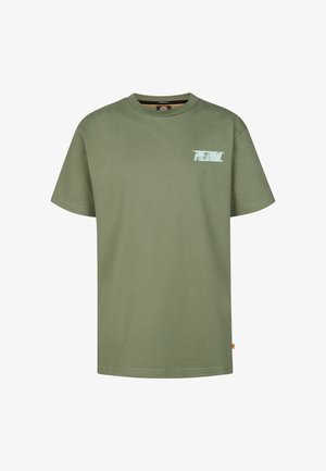 Grøn bomuld T-shirt med korte ærmer og en lille grafik på brystet, parret med lyseblå denimjeans og hvide sneakers.