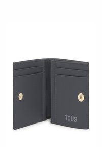 Cartera de cuero negro con cierre a presión, que cuenta con múltiples ranuras para tarjetas y un detalle de logo en relieve. Textura suave y diseño minimalista.