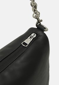 Borsa a tracolla nera in pelle con una superficie liscia, dotata di una chiusura con zip argentata e di una tracolla decorativa in catena.