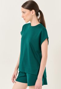 Smaragdgroene top met korte mouwen en een ronde halslijn, gecombineerd met bijpassende shorts, gemaakt van zachte, gestructureerde stof.