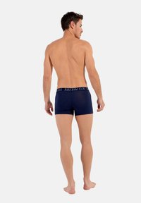 Marinblå boxershorts med en kontrasterande logoband, tillverkade av ett slätt och elastiskt material som ger en tight passform och måttlig täckning.