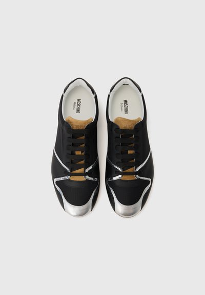Black athletic shoes with a textured fabric upper, silver accents on the toe and side, and brown leather detailing on the tongue.