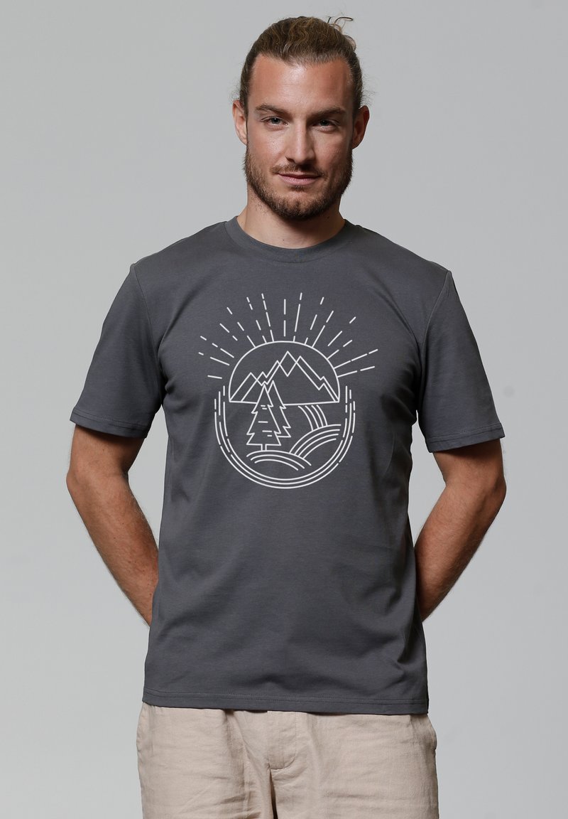 Grijze katoen t-shirt met een witte grafische print van bergen, een boom en zonnestralen in een cirkelontwerp aan de voorkant.