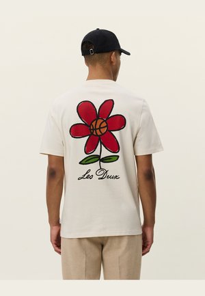 T-shirt in cotone color crema con un grande fiore rosso al centro, all'interno del quale si trova un pallone da basket, e la scritta "Les Deux" sotto il fiore.