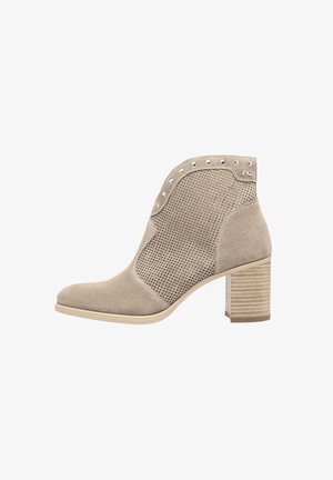 Bottine en suède beige avec panneaux en mesh, bout pointu et clous décoratifs, dotée d'un talon moyen en bloc et d'une semelle texturée.