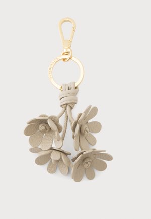 Llavero de cuero beige con cuatro formas de flores colgando de un anillo metálico dorado y cierre sobre un fondo blanco.