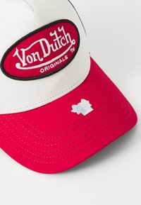 Crvena i bijela bejzbol kapa od pamuka, s ovalnim izvezenim logotipom na kojem piše "Von Dutch" i "Originals" u crnoj i bijeloj boji.
