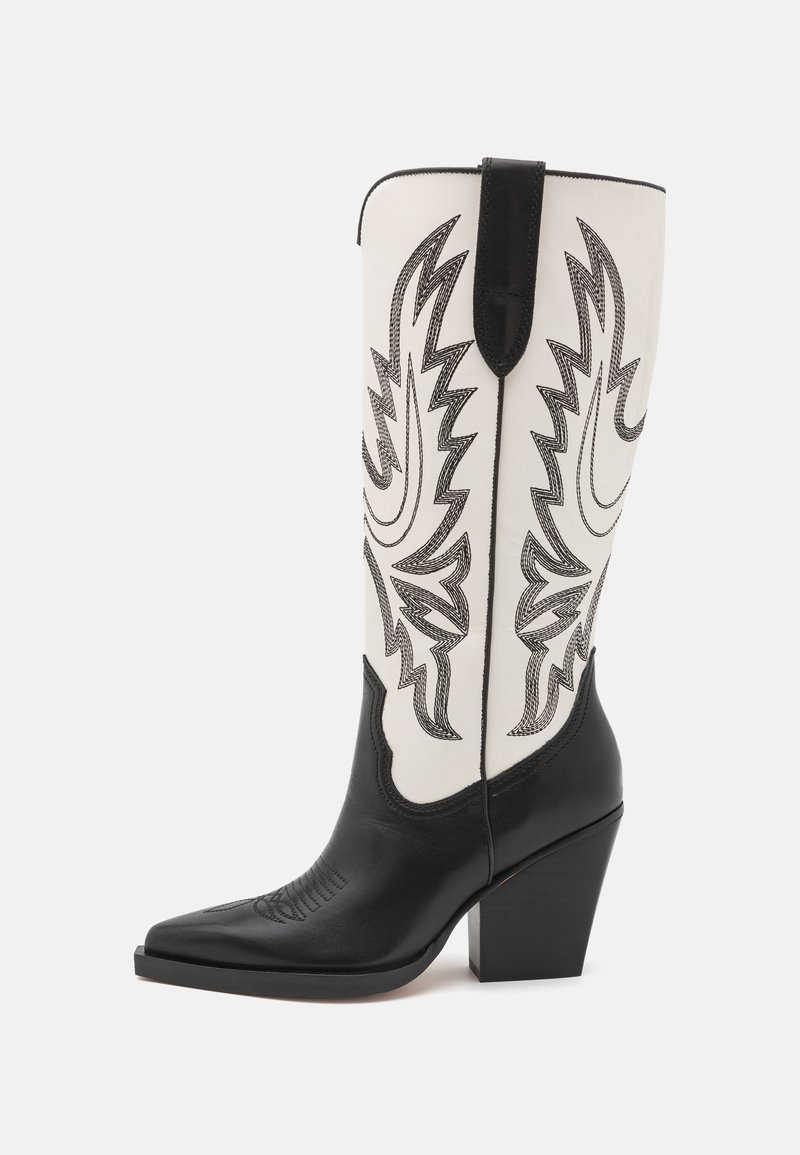 Bota vaquera de cuero negro con punta afilada y una caña blanca que presenta un intrincado bordado negro y un tacón cuadrado.