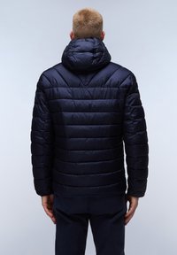 Granatowa kurtka puchowa o pikowanej powierzchni, z kapturem i ściągaczami u mankietów. Posiada poziome i ukośne przeszycia, co dodaje tekstury i zapewnia ciepło.