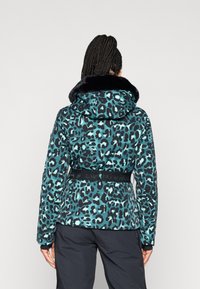 Ζακέτα με σχέδιο λεοπάρ σε teal και μαύρο, με ψεύτικη γούνα στον γιακά, ζώνη στη μέση και μακριά μανίκια με αντίθετες μανσέτες.