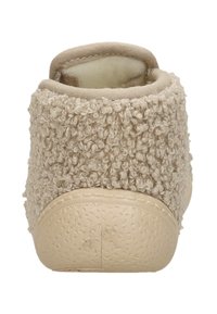 Beige slipper with a textured, fluffy upper, round toe, and a smooth rubber sole. The interior is lined with soft fabric for comfort.