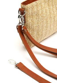 Sac en paille tressée avec un motif en chevron, complété par une bandoulière en cuir marron lisse et des accents en métal argenté.