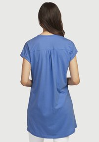 Niebieska bawełniana koszulka T-shirt z krótkimi podwiniętymi rękawami, detalem w postaci zakładki z tyłu oraz wydłużonym dołem, zaprojektowana dla luźnego dopasowania.