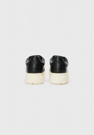 Svarta lädersneakers med texturerad överdel, krämfärgad gummisula och slät finish. Dubbel söm och logga präglad på hälen.