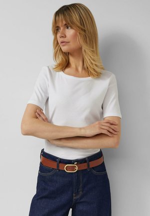 Weißes kurzärmeliges T-Shirt mit rundem Ausschnitt, kombiniert mit dunkelblauen, hoch taillierten Jeans und einem braunen Gürtel mit einer goldenen ovalen Schnalle.