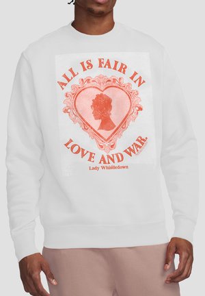 Man wearing white sweatshirt with red heart design and text "All is fair in love and war. Lady Whistledown."
