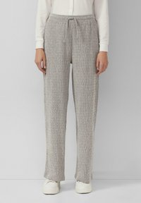 Hellgraue Strickhosen mit einem Kordelzugbund, lockerer Passform und strukturiertem Stoff. Getragen mit weißen Turnschuhen für einen lässigen Look.