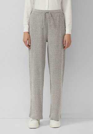Hellgraue Strickhosen mit einem Kordelzugbund, lockerer Passform und strukturiertem Stoff. Getragen mit weißen Turnschuhen für einen lässigen Look.