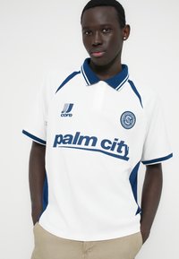 Λευκό πόλο μπλουζάκι με μπλε λεπτομέρειες και ριμπ κολάρο. Διαθέτει το κείμενο "palm city" και λογότυπο στο στήθος. Κατασκευασμένο από υφή υφάσματος.