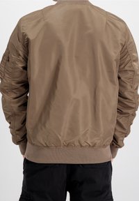 Giacca bomber color khaki con una texture liscia e lucida. Presenta polsini e orlo a coste, vita elastica e ampie tasche laterali.