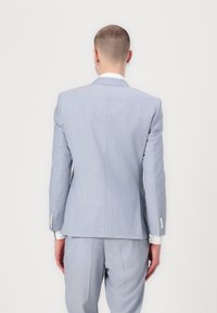 Sacou de culoare albastru deschis, cu un design ajustat, textură netedă și luciu subtil. Prezintă mansete de cămașă albe în contrast și butoane argintii.