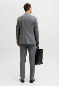 Hall hallisegu ülikond, millel on kohandatud lõige, kombineeritud musta nahast käekoti ja mustade kingadega. Lihtne disain, ilma eristatavate mustriteta.