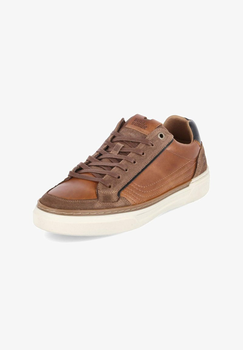 Zapatilla marrón de piel y ante con suela blanca, detalles cosidos, cordones y logo "BULL BOXER" en la lengüeta, inclinada hacia la izquierda.
