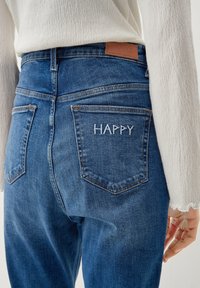 Modré džíny z denimu s vysokým pásom, s koženou nášivkou a vyšitým nápisom "HAPPY" na zadnej vrecku. Priamy strih, stredné pranie.