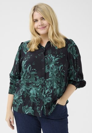 Cămașă neagră cu model floral verde, cu nasturi la față, mâneci bufante și o croială lejeră. Asortată cu blugi din denim închisi.