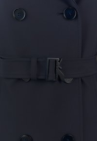 Trench coat navy con design doppiopetto, bottoni neri, cintura in tessuto con fibbia decorativa e texture liscia.