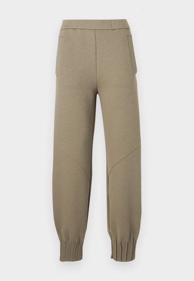 Μπεζ παντελόνι jogger με ελαστικές μπατζάκια, πλαϊνές τσέπες και ραφές στα γόνατα, παρουσιάζεται σε λευκό φόντο.