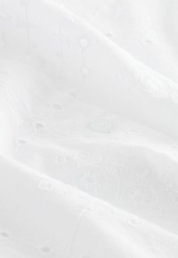 Valge kangas lilltikanditega mustritega, millel on väikesed augud. Tootel on silmapaistev detail - helesinine nupp.