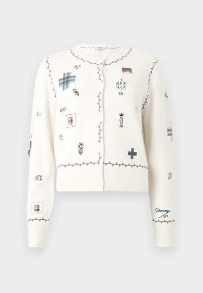 Άσπρη ζακέτα με κουμπιά και μπορντό ραμμένα περιθώρια με διάφορα μικρά κεντημένα σύμβολα και γράμματα σε μπλε, μπορντό και μπεζ.