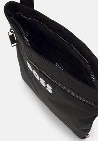 Black nylon pouch with a textured surface, featuring a top zipper closure and prominent white "BOSS" logo on the front. Interior includes compartments.
