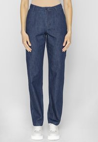 Granatowe dżinsy o prostym kroju, zapinane na guzik, z szlufkami na pasek, zestawione z białymi trampkami. Minimalna tekstura, codzienny design.