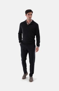 Dunkelgrauer Wollpullover mit einem halben Reißverschluss-Kragen, kombiniert mit maßgeschneiderten schwarzen Hosen und grauen Wildlederstiefeln. Einfaches und modernes Design.